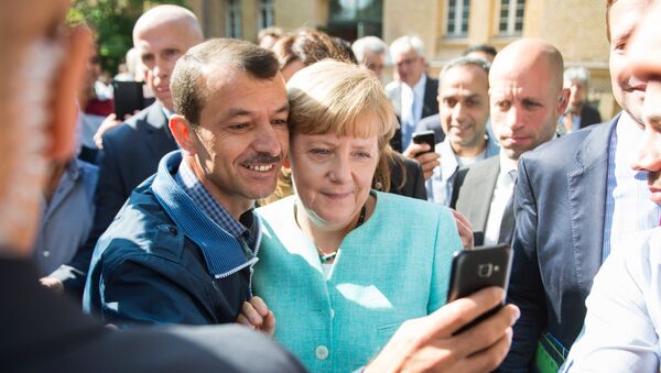 Asylum seeker (C, L) takes a selfie picture with German Chancellor Angela Merkel (C, R) following Merkel's visit at a branch of the Federal Office for Migration and Refugees and a camp for asylum-seekers in Berlin on September 10, 2015. - Sputnik International