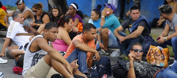 Cubans interrupt traffic sitting on a portion of Fifth Avenue near Ecuador's embassy to express discontent with a new visa rule that now requires Cubans have a visa to visit the South American country, in Havana, Cuba, Saturday, Nov. 28, 2015 - Sputnik International