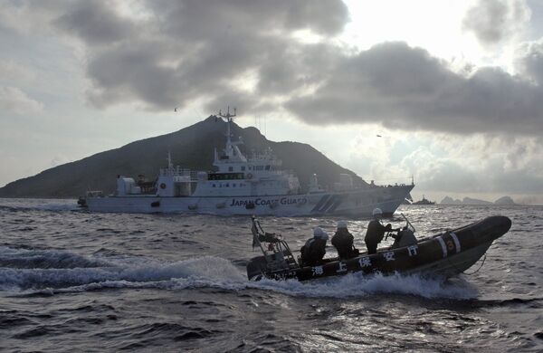 In this Sunday, Aug. 18, 2013 file photo, Japanese Coast Guard boat and vessel sail alongside Japanese activists' fishing boat, not in photo, warning the activists away from a group of disputed islands called Diaoyu by China and Senkaku by Japan In this Sunday, Aug. 18, 2013 file photo, Japanese Coast Guard boat and vessel sail alongside Japanese activists' fishing boat, not in photo, warning the activists away from a group of disputed islands called Diaoyu by China and Senkaku by Japan - Sputnik International