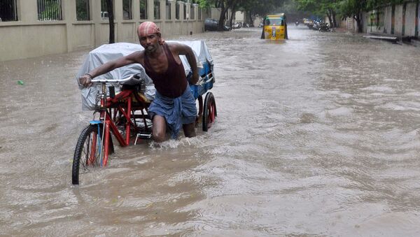 An Indian labourer pushes his cycle trishaw through floodwaters in Chennai on December 1, 2015, during a downpour of heavy rain in the southern Indian city - Sputnik International