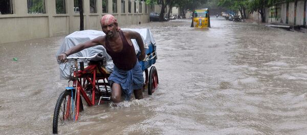 An Indian labourer pushes his cycle trishaw through floodwaters in Chennai on December 1, 2015, during a downpour of heavy rain in the southern Indian city - Sputnik International