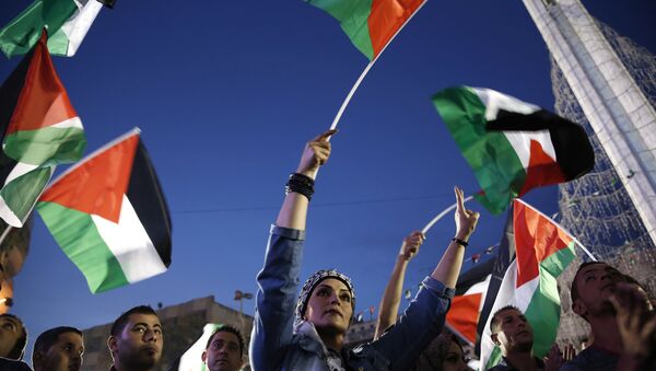 Palestinians wave their national flags as they watch a live-screening of president Mahmud Abbas' speech followed by the raising of the Palestinian flag at the United Nations headquarters in New York, on September 30, 2015 in the city of Ramallah - Sputnik International