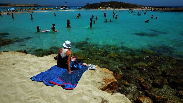 A woman sit on the sand as other people enjoy the sea at Nissi Beach in the famous southeastern coastal resort of Ayia Napa, Cyprus, Saturday, June 14, 2014 - Sputnik International