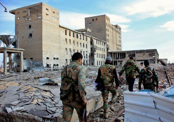Syrian army soldiers patrol near a building previously used for storing seeds in the countryside of Deir Hafer, a former bastion of Daesh, near the northern Syrian city of Aleppo on December 2, 2015 - Sputnik International