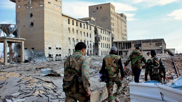 Syrian army soldiers patrol near a building previously used for storing seeds in the countryside of Deir Hafer, a former bastion of Daesh, near the northern Syrian city of Aleppo on December 2, 2015 - Sputnik International