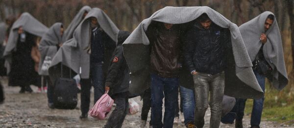 Migrants shield from rain with blankets as they walk after crossing the border from Greece into Macedonia, near Gevgelija, Macedonia, November 27, 2015 Migrants shield from rain with blankets as they walk after crossing the border from Greece into Macedonia, near Gevgelija, Macedonia, November 27, 2015 - Sputnik International