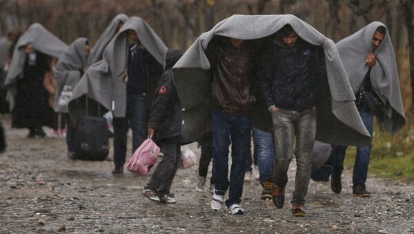 Migrants shield from rain with blankets as they walk after crossing the border from Greece into Macedonia, near Gevgelija, Macedonia, November 27, 2015 - Sputnik International