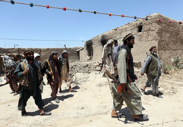 In this Thursday, May 21, 2015 file photo, local militia group fighters walk past a building torched by Taliban fighters at Talawka village in Kunduz province, north of Kabul, Afghanistan In this Thursday, May 21, 2015 file photo, local militia group fighters walk past a building torched by Taliban fighters at Talawka village in Kunduz province, north of Kabul, Afghanistan - Sputnik International