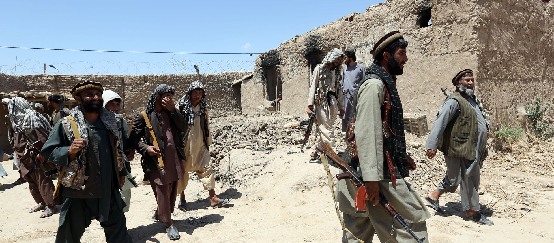 In this Thursday, May 21, 2015 file photo, local militia group fighters walk past a building torched by Taliban fighters at Talawka village in Kunduz province, north of Kabul, Afghanistan - Sputnik International, 1920, 08.08.2021