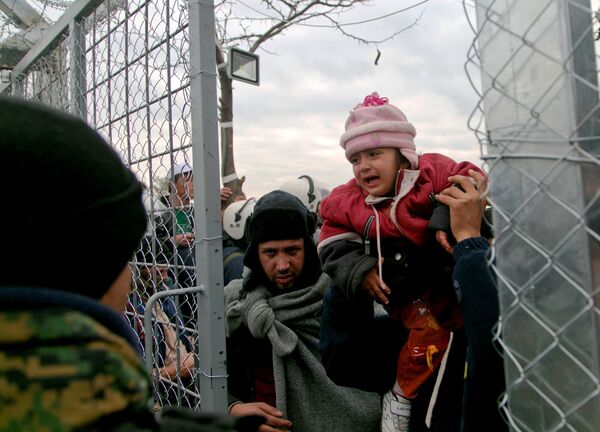 A migrant is child carried into Macedonia, near the southern Macedonian town of Gevgelija, Friday, Dec. 4, 2015. - Sputnik International