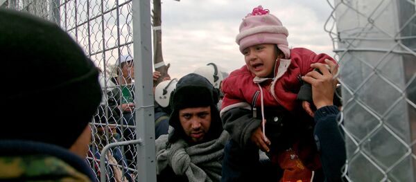 A migrant is child carried into Macedonia, near the southern Macedonian town of Gevgelija, Friday, Dec. 4, 2015. - Sputnik International
