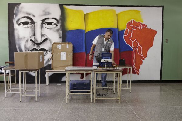 A worker of the National Electoral Council (CNE) configures a voting machine in front of a mural depicting Venezuela's late President Hugo Chavez at a school in Caracas, December 4, 2015. Venezuela will hold parliamentary elections on December 6. A worker of the National Electoral Council (CNE) configures a voting machine in front of a mural depicting Venezuela's late President Hugo Chavez at a school in Caracas, December 4, 2015. Venezuela will hold parliamentary elections on December 6. - Sputnik International