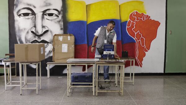 A worker of the National Electoral Council (CNE) configures a voting machine in front of a mural depicting Venezuela's late President Hugo Chavez at a school in Caracas, December 4, 2015. Venezuela will hold parliamentary elections on December 6. - Sputnik International