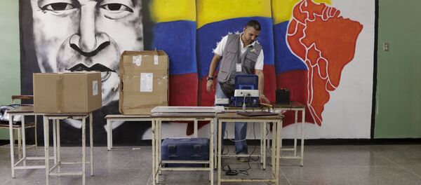 A worker of the National Electoral Council (CNE) configures a voting machine in front of a mural depicting Venezuela's late President Hugo Chavez at a school in Caracas, December 4, 2015. Venezuela will hold parliamentary elections on December 6. A worker of the National Electoral Council (CNE) configures a voting machine in front of a mural depicting Venezuela's late President Hugo Chavez at a school in Caracas, December 4, 2015. Venezuela will hold parliamentary elections on December 6. - Sputnik International