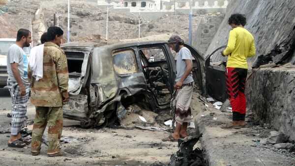 People look at the wreckage of a car at the site of the a car bomb attack that killed the governor of Yemen's southern port city of Aden December 6, 2015 - Sputnik International