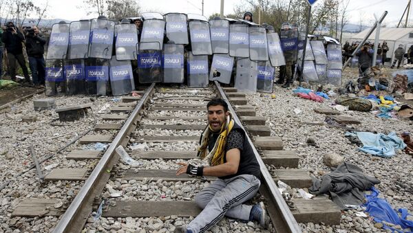 A stranded migrant reacts in front of a Macedonian police cordon as they clash after a migrant was injured when he climbed on top of a train wagon, near the village of Idomeni, Greece, November 28, 2015. - Sputnik International