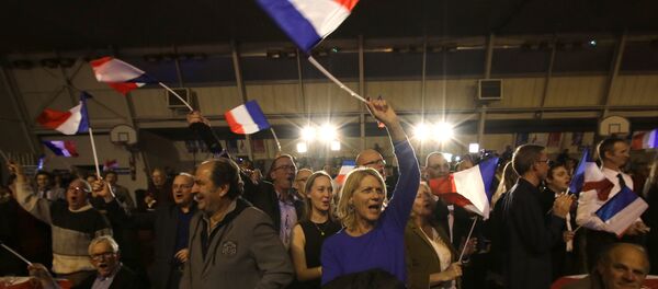 Supporters of far right National Front party regional leader for southeastern France, Marion Marechal-Le Pen, wave flags at a meeting after the results of the first round of the regional elections, in Carpentras, southern France - Sputnik International