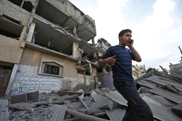 Palestinian talks on a mobile phone as he walks on the rubble of a damaged house following an overnight Israeli missile strike in Gaza City, Tuesday, July 15, 2014 Palestinian talks on a mobile phone as he walks on the rubble of a damaged house following an overnight Israeli missile strike in Gaza City, Tuesday, July 15, 2014 - Sputnik International