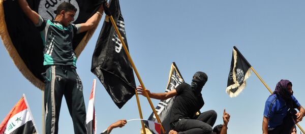 FILE - Masked Sunni protesters wave Islamist flags while others chant slogans at an anti-government rally in Fallujah, Iraq - Sputnik International