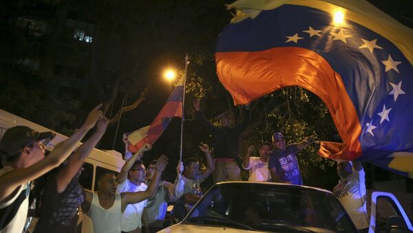 Supporters of the opposition Democratic Unity coalition wave a Venezuelan national flag from a car while they celebrate their victory on a street in Caracas December 7, 2015 - Sputnik International