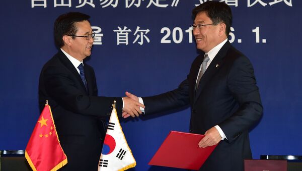Chinese Commerce Minister Gao Hucheng (L) shakes hands with South Korean Trade Minister Yoon Sang-Jick (R) during a signing ceremony for a bilateral free trade agreement at a hotel in Seoul on June 1, 2015 - Sputnik International