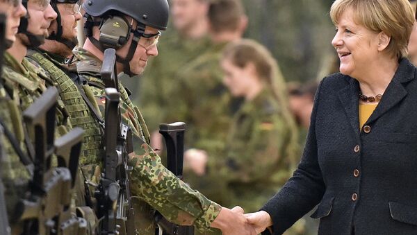 Немецкий канцлер Ангела Меркель жмет руку солдату во время визита в часть медико-санитарной службы армии Германии в городе Лер  - Sputnik International