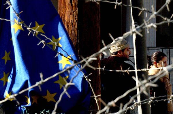 Turkish Cypriot couple, seen behind barbed wire and an EU flag, as they cross the Ledra Palace checkpoint in Nicosia, Cyprus. - Sputnik International