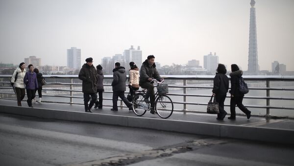 North Koreans walk along a bridge that takes them over the Taedong River on Wednesday, Dec. 2, 2015, in Pyongyang, North Korea. Seen in the background is the Juche Tower - Sputnik International