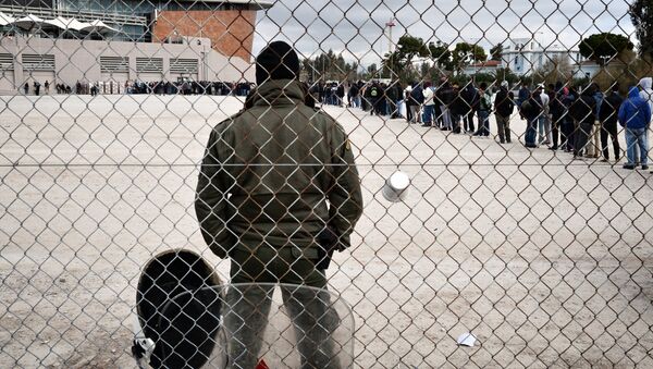 A riot policeman stands guard at a temporary housing facility for migrants nad refugees located in a former Olympic hall in Faliro suburb of Athens on December 11, 2015. - Sputnik International