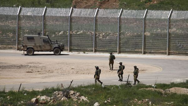 Israeli soldiers walk near a fence in the Israeli occupied Golan Heights on the border with war-torn Syria - Sputnik International