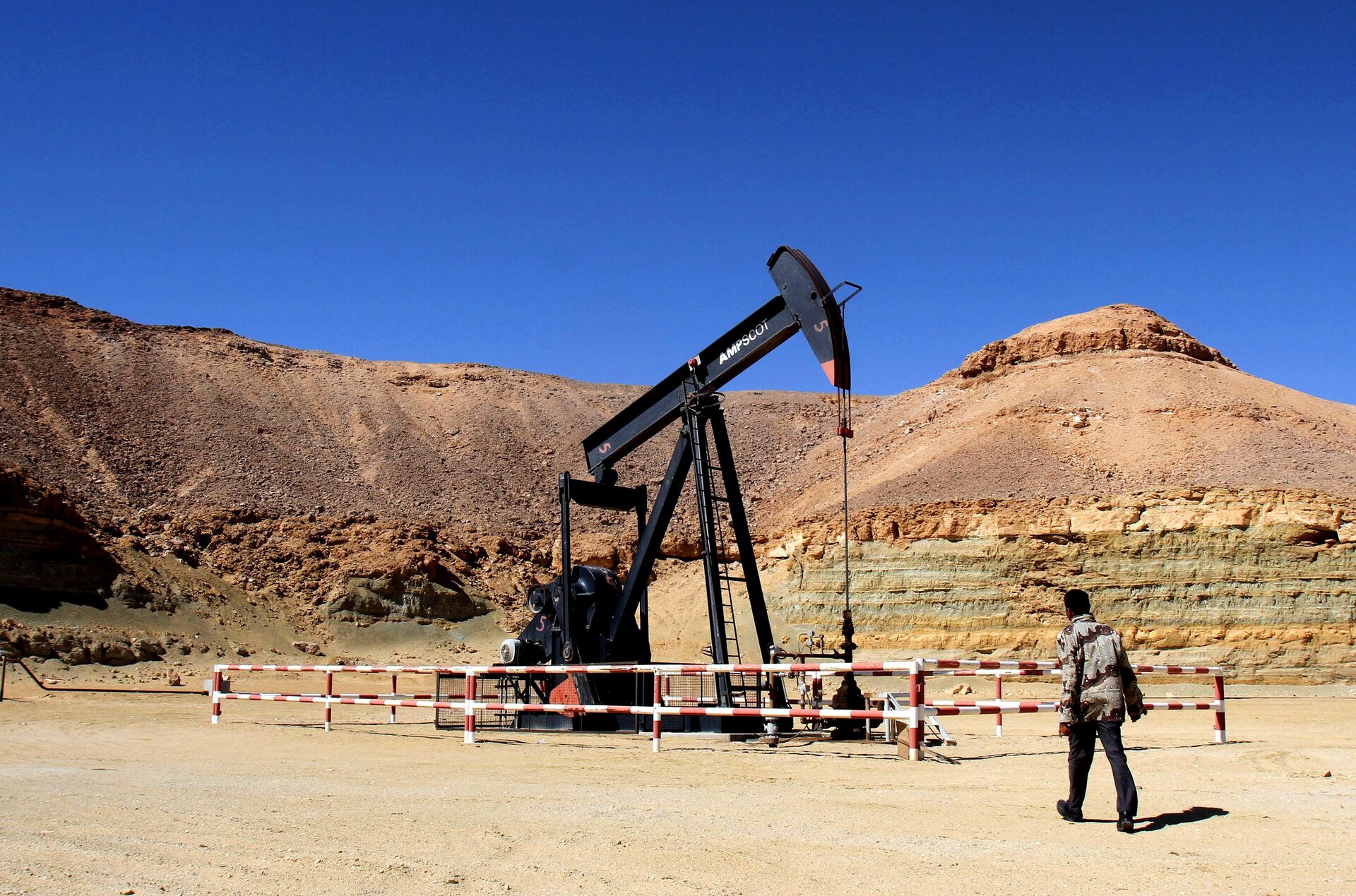 A Libyan security member walks by an oil drill on March 23, 2013 at the al-Ghani oil field, near the city of Waddan in the central Al-Jufrah province. - Sputnik International, 1920, 12.09.2022