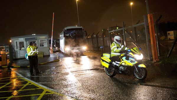 A police motorcycle rider (R) escorts a convoy of buses carrying Syrian refugees as they leave Glasgow airport, in Scotland on November 17, 2015 - Sputnik International