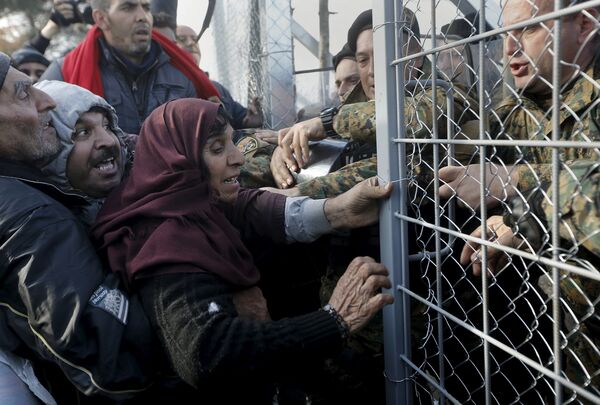 Syrian refugees struggle to enter Macedonia through a narrow border crossing as Macedonian policemen try to shut a metal gate near to the Greek village of Idomeni December 4, 2015. Syrian refugees struggle to enter Macedonia through a narrow border crossing as Macedonian policemen try to shut a metal gate near to the Greek village of Idomeni December 4, 2015. - Sputnik International