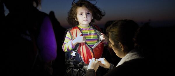 A child gets assistance to remove her life jacket upon her arrival on an inflatable boat carrying migrants on the Greek island of Kos after crossing a part of the Aegean Sea between Turkey and Greece on August 13, 2015. A child gets assistance to remove her life jacket upon her arrival on an inflatable boat carrying migrants on the Greek island of Kos after crossing a part of the Aegean Sea between Turkey and Greece on August 13, 2015. - Sputnik International