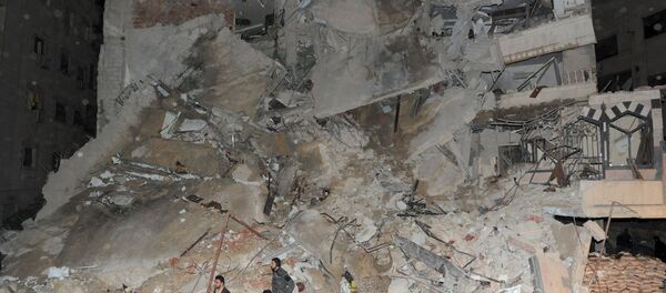 Members of Syrian security services and soldiers stand in front of a damaged building that was hit by an Israeli strike, killing a Lebanese militant leader Samir Qantar, in the Damascus district of Jaramana, Syria in this handout picture provided by SANA on December 20, 2015 - Sputnik International