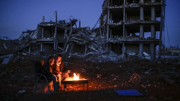 Kurdish men sit near bonfire near a destroyed building, in the Syrian Kurdish town of Kobane, also known as Ain al-Arab - Sputnik International