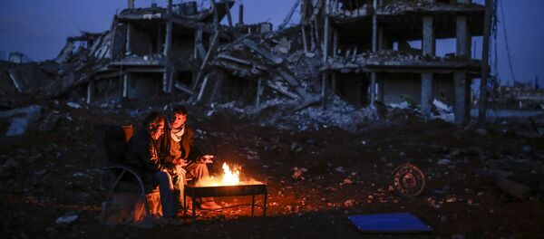 Kurdish men sit near bonfire near a destroyed building, in the Syrian Kurdish town of Kobane, also known as Ain al-Arab - Sputnik International