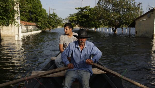 Victor Ferreira, who is displaced by flooding, rows his boat through the streets of his Jukyty neighborhood in Asuncion, Paraguay, Wednesday, Dec. 23, 2015. - Sputnik International