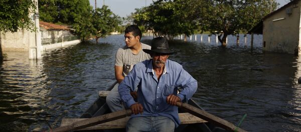 Victor Ferreira, who is displaced by flooding, rows his boat through the streets of his Jukyty neighborhood in Asuncion, Paraguay, Wednesday, Dec. 23, 2015. - Sputnik International