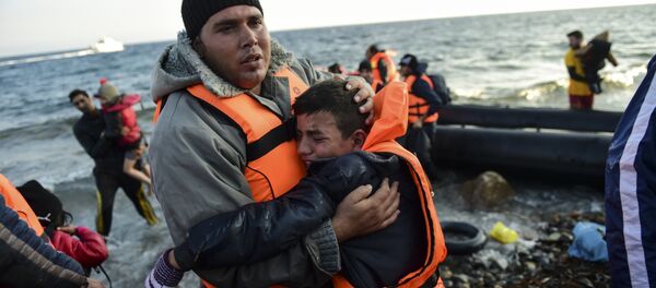Peopl react after arriving on the Greek island of Lesbos along with other migrants and refugees, on November 17, 2015, after crossing the Aegean Sea from Turkey - Sputnik International