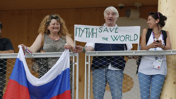 Visitors hold a banner and a Russian flag as Russian President Vladimir Putin arrives for a visit at the Russian pavilion at the 2015 Expo in Rho, near Milan, Italy, Wednesday, June 10, 2015 - Sputnik International