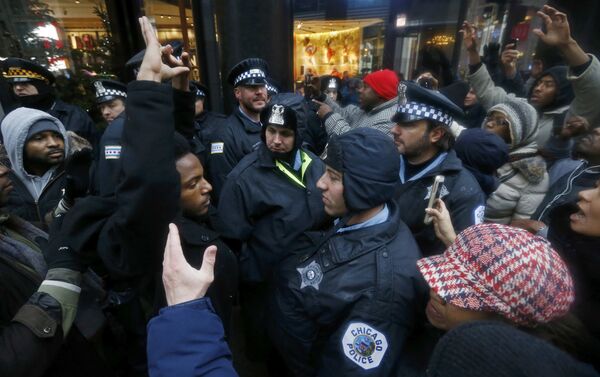 Demonstators hold their hands up in front of Chicago Police officers during protest of last year's shooting death of black teenager Laquan McDonald by a white policeman and the city's handling of the case in the downtown shopping district of Chicago, Illinois, November 27, 2015 - Sputnik International