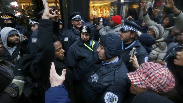 Demonstators hold their hands up in front of Chicago Police officers during protest of last year's shooting death of black teenager Laquan McDonald by a white policeman and the city's handling of the case in the downtown shopping district of Chicago, Illinois, November 27, 2015 - Sputnik International