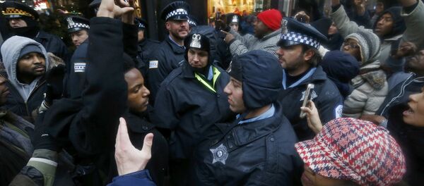 Demonstators hold their hands up in front of Chicago Police officers during protest of last year's shooting death of black teenager Laquan McDonald by a white policeman and the city's handling of the case in the downtown shopping district of Chicago, Illinois, November 27, 2015 Demonstators hold their hands up in front of Chicago Police officers during protest of last year's shooting death of black teenager Laquan McDonald by a white policeman and the city's handling of the case in the downtown shopping district of Chicago, Illinois, November 27, 2015 - Sputnik International