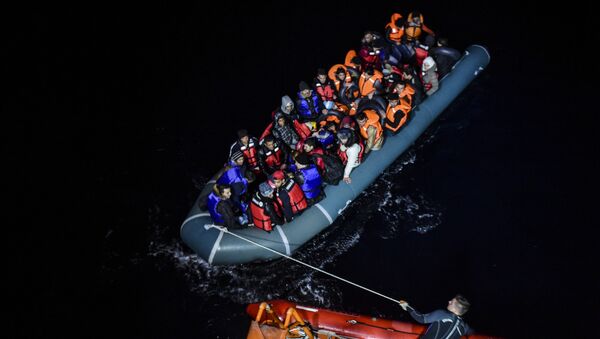 File photo of a member of the Turkish Coast Guard pulls an inflatable dinghy transporting Syrian migrants attempting to reach the Greek island of Chios, in the Agean Sea near Izmir in the night of December 9 to December 10, 2015 - Sputnik International