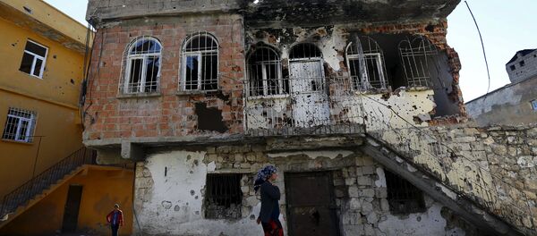 A woman walks past a building which was damaged during the security operations and clashes between Turkish security forces and Kurdish militants, in the southeastern town of Silvan in Diyarbakir province, Turkey, December 7, 2015. - Sputnik International