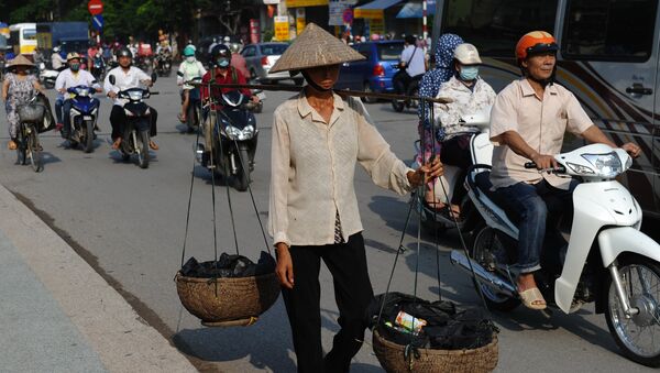 This picture taken on September 10, 2015 shows a migrant worker (C) carrying collected items for recycling walking along a road in downtown Hanoi - Sputnik International