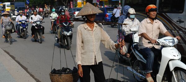 This picture taken on September 10, 2015 shows a migrant worker (C) carrying collected items for recycling walking along a road in downtown Hanoi - Sputnik International