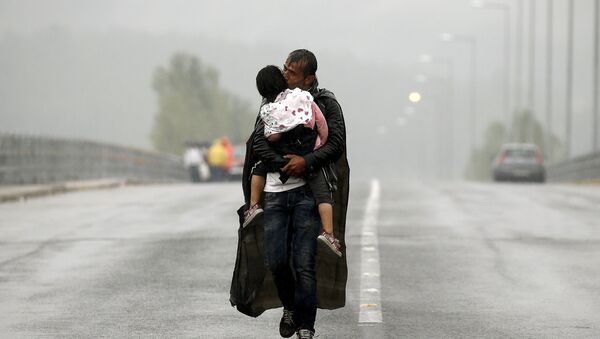 A Syrian refugee kisses his daughter as he walks through a rainstorm towards Greece's border with Macedonia, near the Greek village of Idomeni, September 10, 2015 - Sputnik International