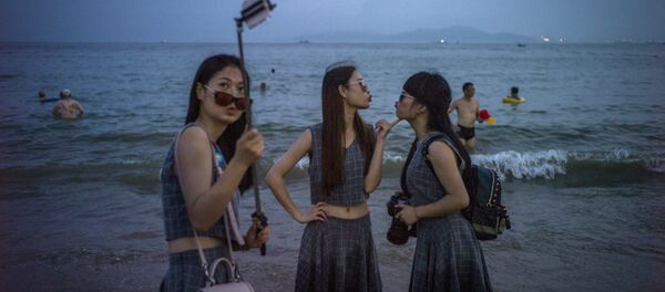 Chinese women pose for a picture on the beach in Qingdao, eastern China's Shandong province on July 24, 2015 Chinese women pose for a picture on the beach in Qingdao, eastern China's Shandong province on July 24, 2015 - Sputnik International
